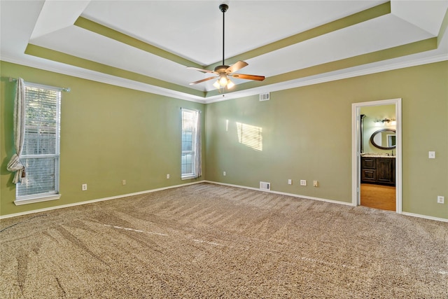 spare room featuring a tray ceiling, light carpet, and ceiling fan