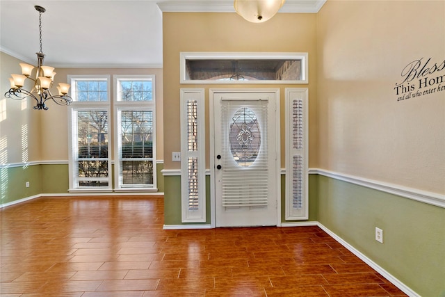 entrance foyer with a wealth of natural light, crown molding, and a notable chandelier