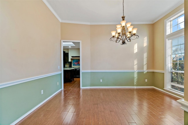 unfurnished room with hardwood / wood-style flooring, ornamental molding, and a chandelier