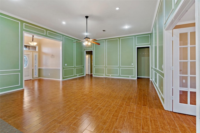 empty room with ceiling fan, wood-type flooring, and ornamental molding