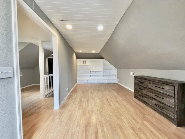 additional living space featuring light wood-type flooring and vaulted ceiling