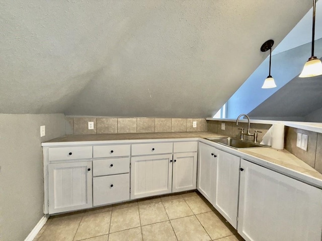 kitchen featuring vaulted ceiling, white cabinetry, hanging light fixtures, and sink