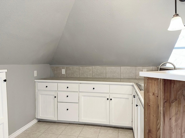 interior space featuring a textured ceiling, lofted ceiling, and tile patterned floors