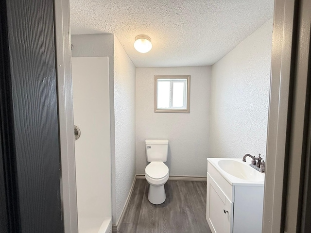 bathroom featuring wood-type flooring, toilet, vanity, and a textured ceiling