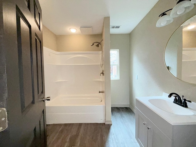 bathroom with bathtub / shower combination, hardwood / wood-style floors, and vanity