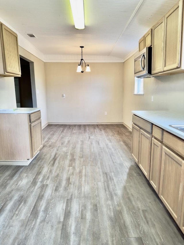 kitchen with an inviting chandelier, light hardwood / wood-style floors, light brown cabinets, hanging light fixtures, and ornamental molding