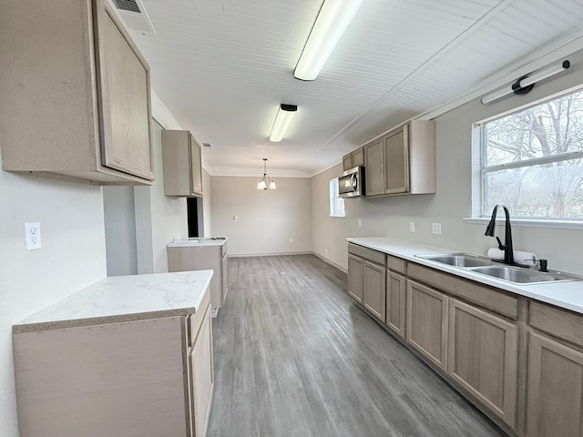 kitchen featuring light hardwood / wood-style floors, a notable chandelier, pendant lighting, crown molding, and sink