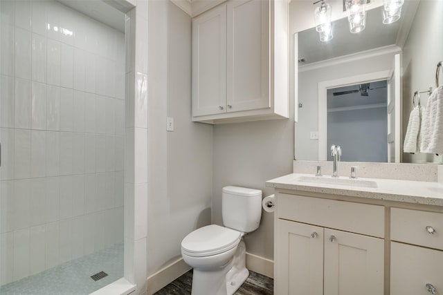 bathroom with hardwood / wood-style floors, vanity, crown molding, toilet, and a tile shower