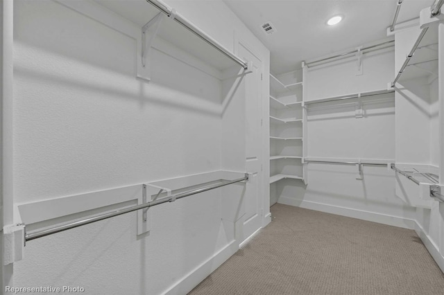 walk in closet with light carpet