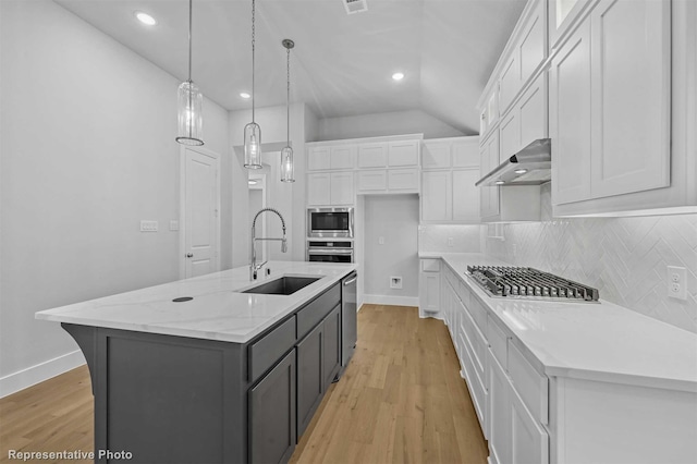 kitchen featuring pendant lighting, sink, white cabinetry, and an island with sink