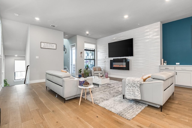 living room featuring plenty of natural light, a fireplace, and light hardwood / wood-style flooring