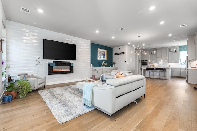 living room with a chandelier, a fireplace, and light hardwood / wood-style flooring