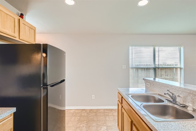 kitchen featuring black fridge, light brown cabinetry, and sink