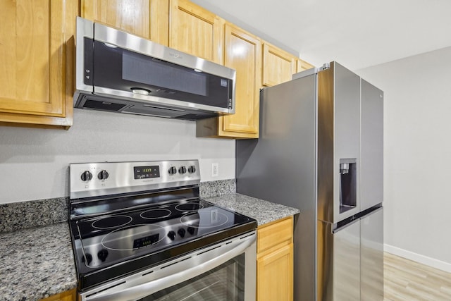 kitchen with appliances with stainless steel finishes, light stone countertops, and light hardwood / wood-style floors