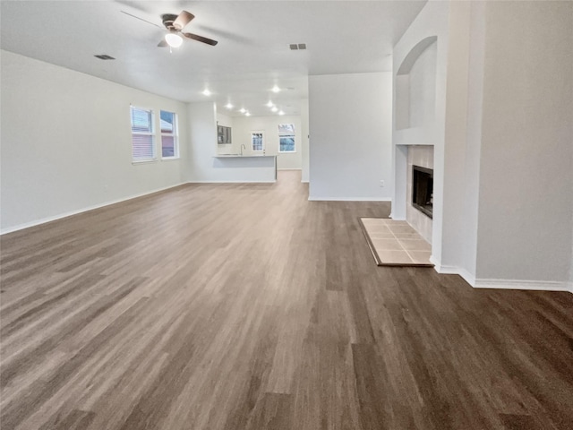 unfurnished living room featuring a fireplace, wood-type flooring, and ceiling fan