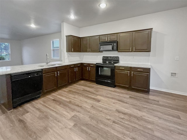 kitchen with sink, light hardwood / wood-style flooring, a wealth of natural light, and black appliances