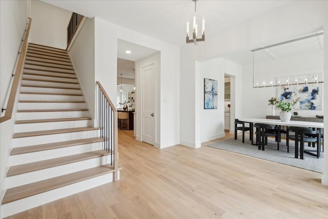 stairs featuring hardwood / wood-style flooring and an inviting chandelier