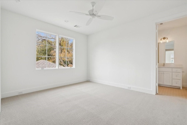 unfurnished bedroom with ceiling fan, light carpet, and ensuite bath