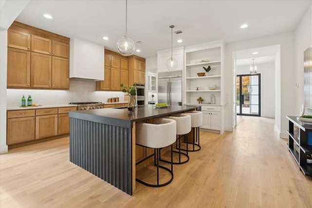 kitchen featuring a kitchen island with sink, sink, stainless steel appliances, and light hardwood / wood-style flooring