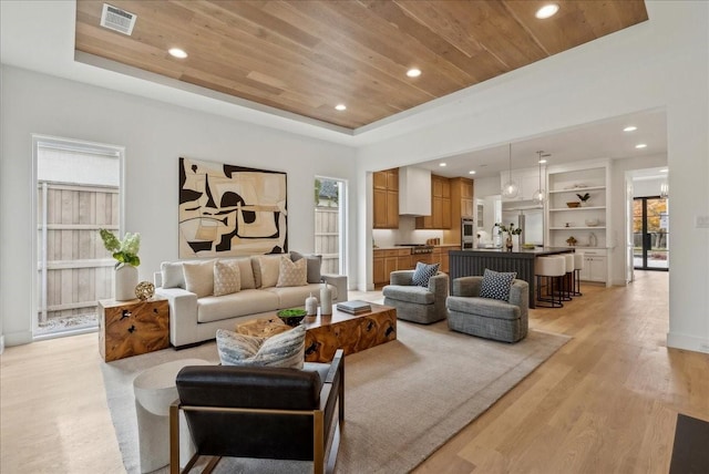 living room featuring a tray ceiling, plenty of natural light, wooden ceiling, and light hardwood / wood-style floors