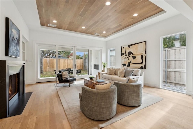 living room with a raised ceiling, french doors, wood ceiling, and light wood-type flooring