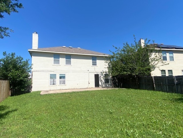 back of house with a yard, a chimney, and fence