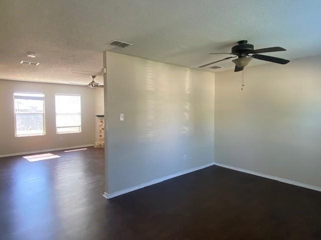 unfurnished room with a textured ceiling, visible vents, baseboards, and a ceiling fan