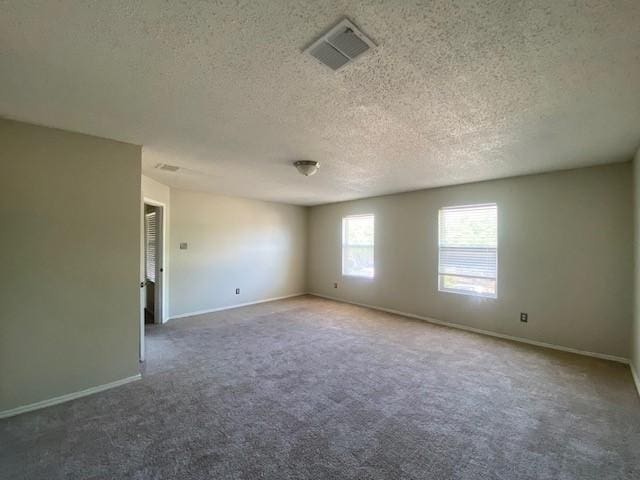 carpeted spare room featuring a textured ceiling, baseboards, and visible vents