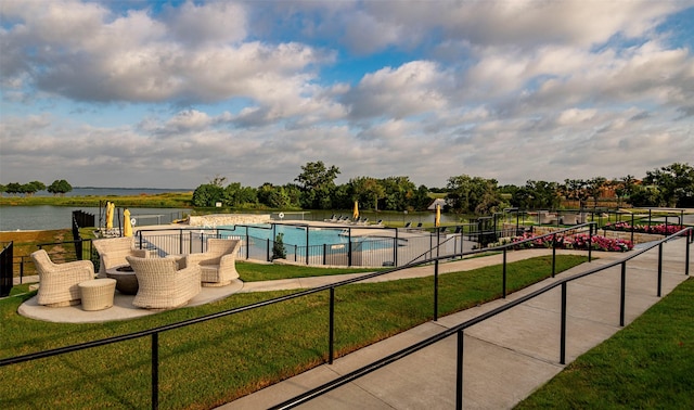 view of pool featuring a patio area, a yard, and a water view