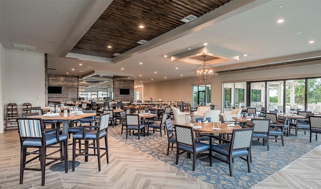 dining room with a raised ceiling, light parquet flooring, and an inviting chandelier