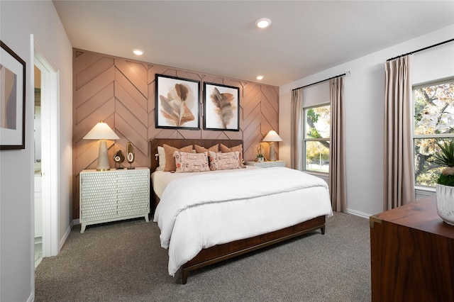 carpeted bedroom featuring ensuite bathroom and wooden walls