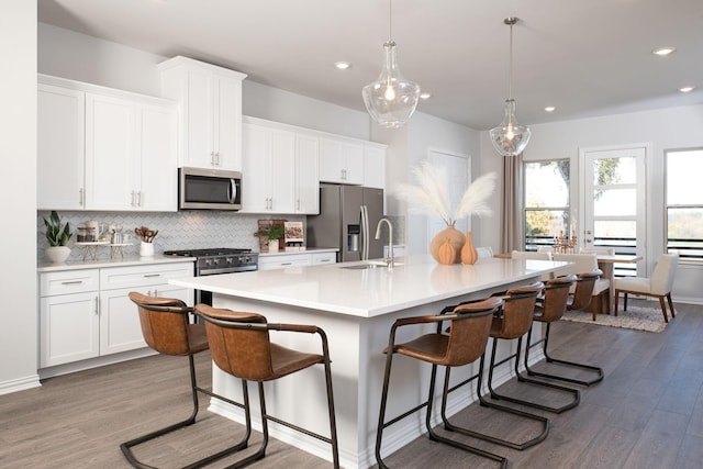 kitchen featuring a kitchen breakfast bar, a center island with sink, white cabinets, and appliances with stainless steel finishes