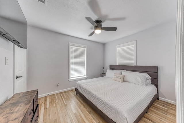 bedroom with a textured ceiling, light hardwood / wood-style flooring, and ceiling fan