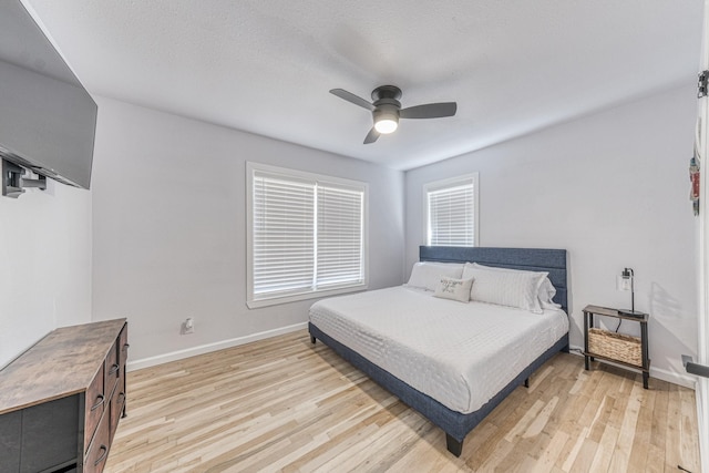 bedroom with a textured ceiling, light hardwood / wood-style flooring, and ceiling fan