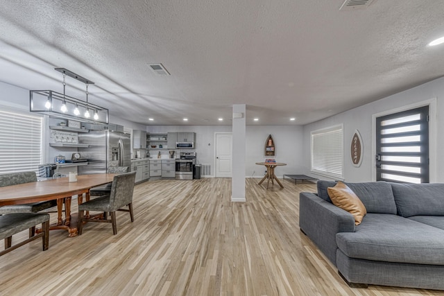 living room with a textured ceiling and light wood-type flooring