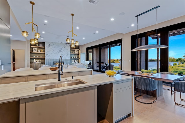 kitchen featuring pendant lighting, french doors, a water view, sink, and built in features