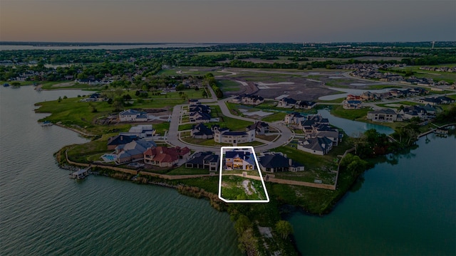 aerial view at dusk featuring a water view