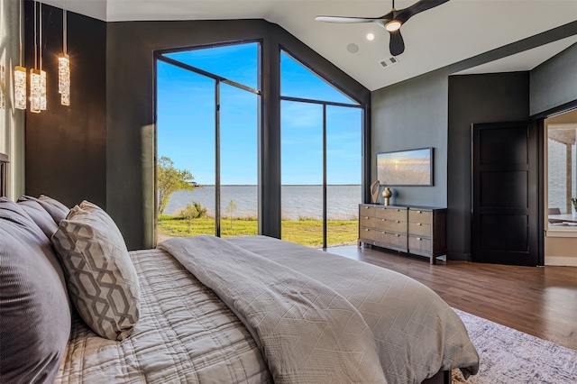 bedroom featuring hardwood / wood-style flooring, ceiling fan, a water view, and vaulted ceiling