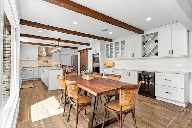 dining room featuring a barn door, beamed ceiling, and beverage cooler