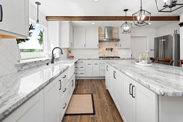 kitchen with beam ceiling, white cabinetry, wall chimney exhaust hood, decorative light fixtures, and appliances with stainless steel finishes