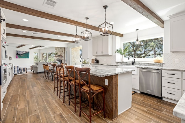 kitchen featuring dishwasher, white cabinets, a kitchen island, and a breakfast bar area