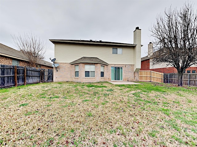 back of house featuring a fenced backyard, a yard, and brick siding