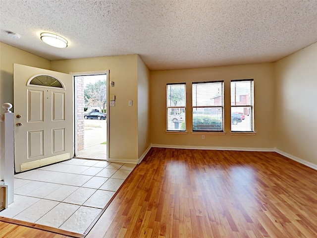 entrance foyer with light wood-style floors, a wealth of natural light, a textured ceiling, and baseboards