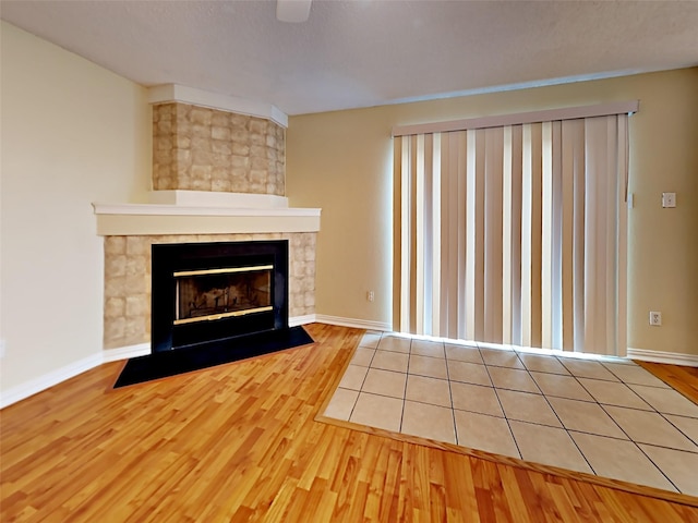 unfurnished living room featuring a fireplace, baseboards, and wood finished floors