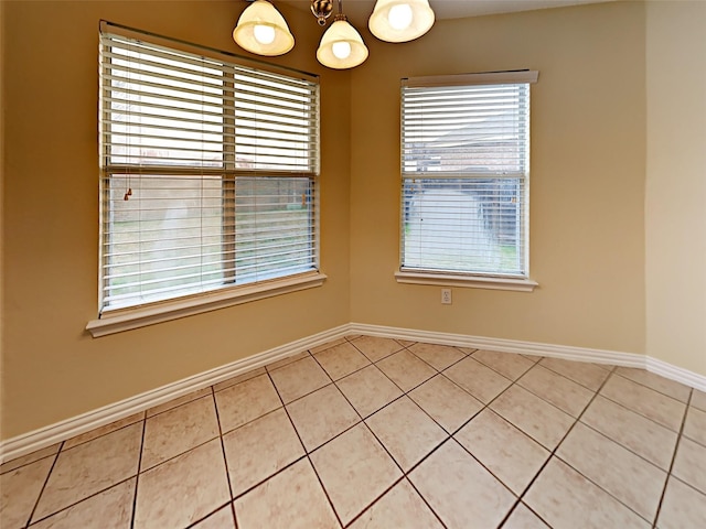 unfurnished room with light tile patterned floors, baseboards, and a chandelier