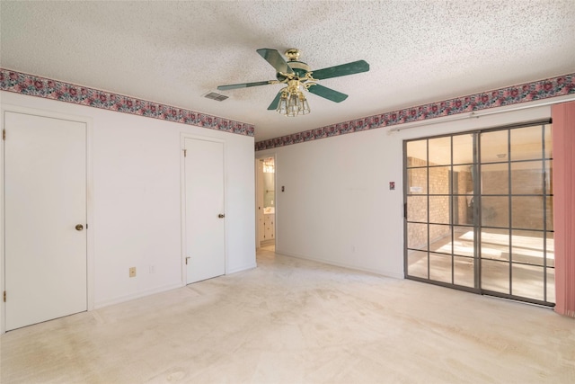 unfurnished bedroom featuring ceiling fan, light colored carpet, and a textured ceiling