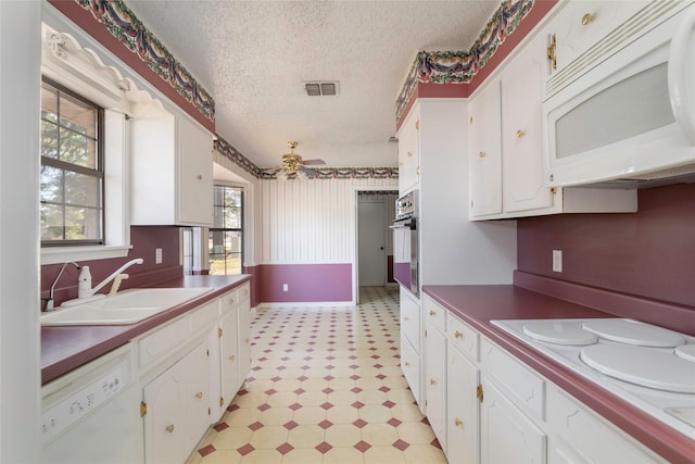 kitchen with sink, white cabinets, a textured ceiling, white appliances, and ceiling fan