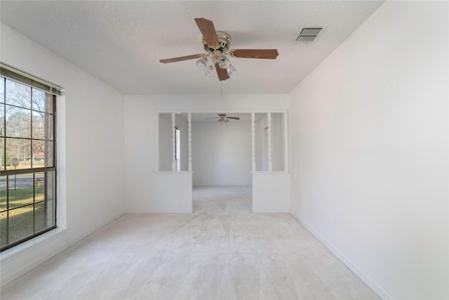 unfurnished room featuring a textured ceiling, ceiling fan, and light colored carpet