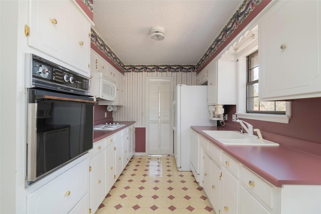 kitchen with white appliances, white cabinetry, a textured ceiling, and sink