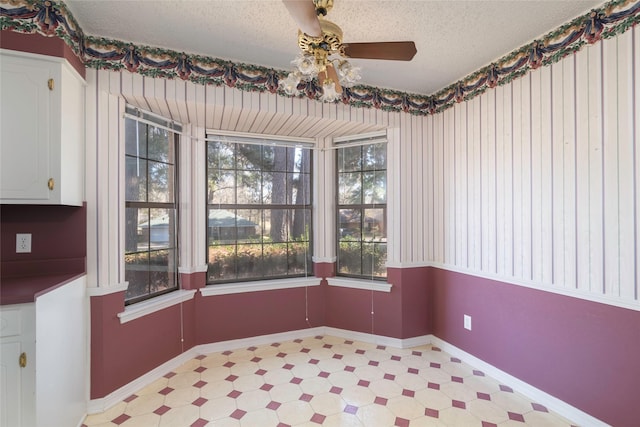 unfurnished dining area featuring a textured ceiling and ceiling fan